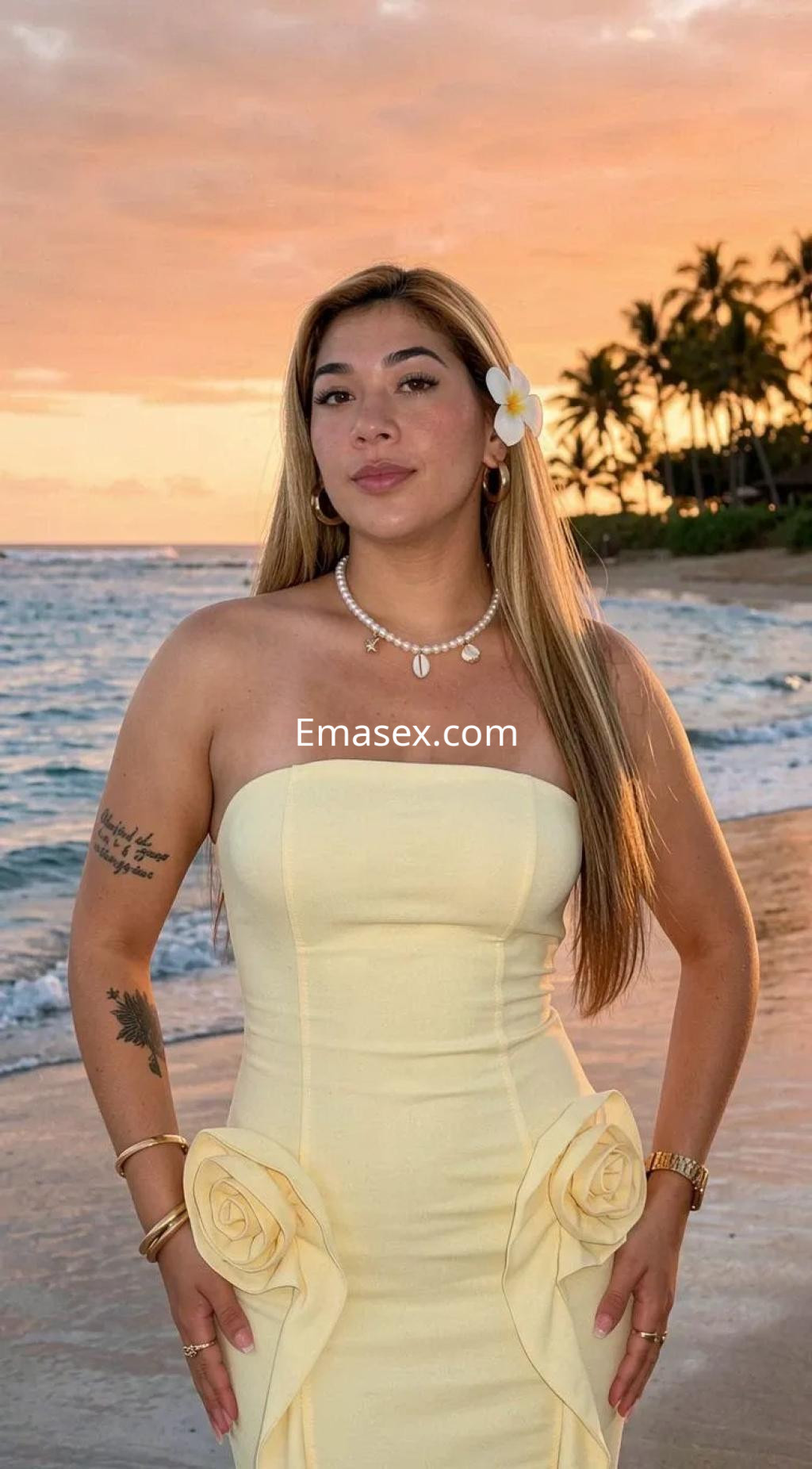 La puta lleva un vestido amarillo sin mangas con detalles florales, posando frente al mar en Vigo al atardecer.