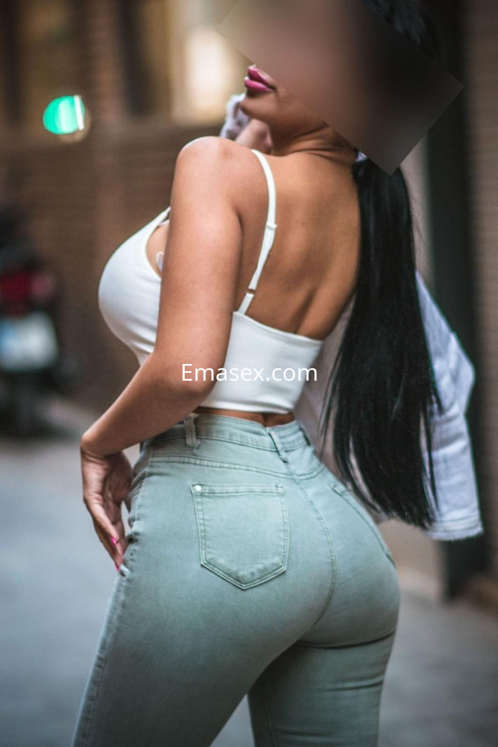 Puta en Valencia posa con blusa blanca y jeans ajustados, mostrando su figura en un entorno urbano.