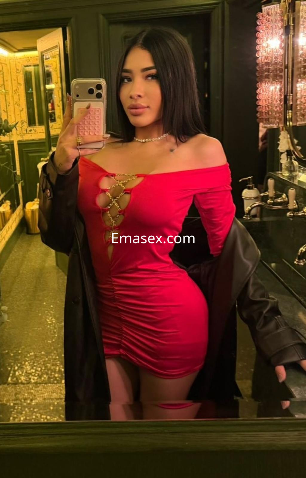 Escort en Gijón con cabello lacio y oscuro, vistiendo un vestido rojo ajustado y posando en un baño elegante.