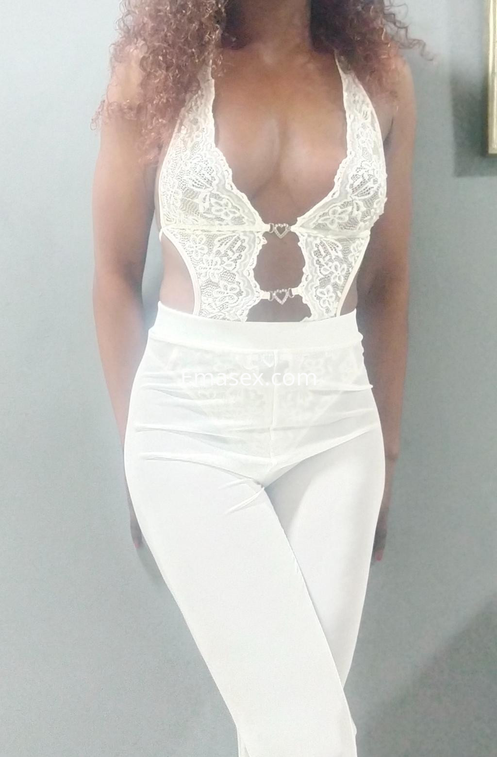 Puta de piel oscura con cabello rizado, usando un conjunto blanco de encaje y pantalones ajustados en Madrid.