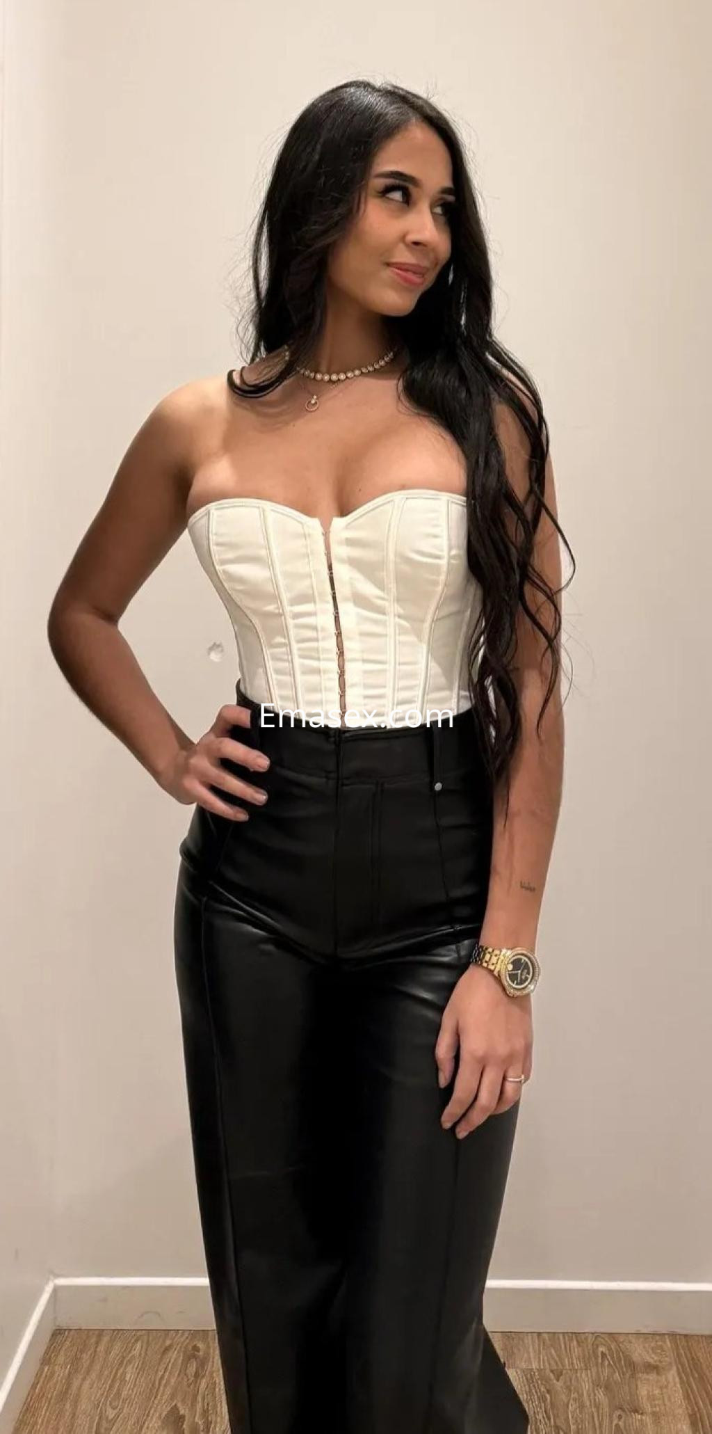 Escort en Zaragoza luciendo un corsé blanco y pantalones de cuero negro, con cabello largo y suelto.