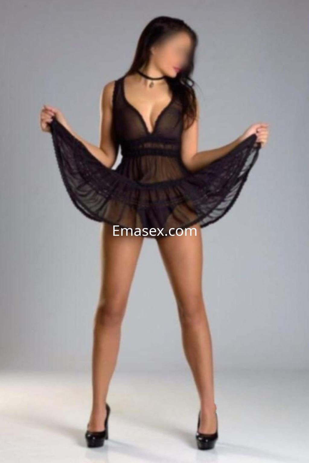 Puta en Barcelona luciendo un vestido negro semitransparente y tacones altos, posando con una actitud seductora.
