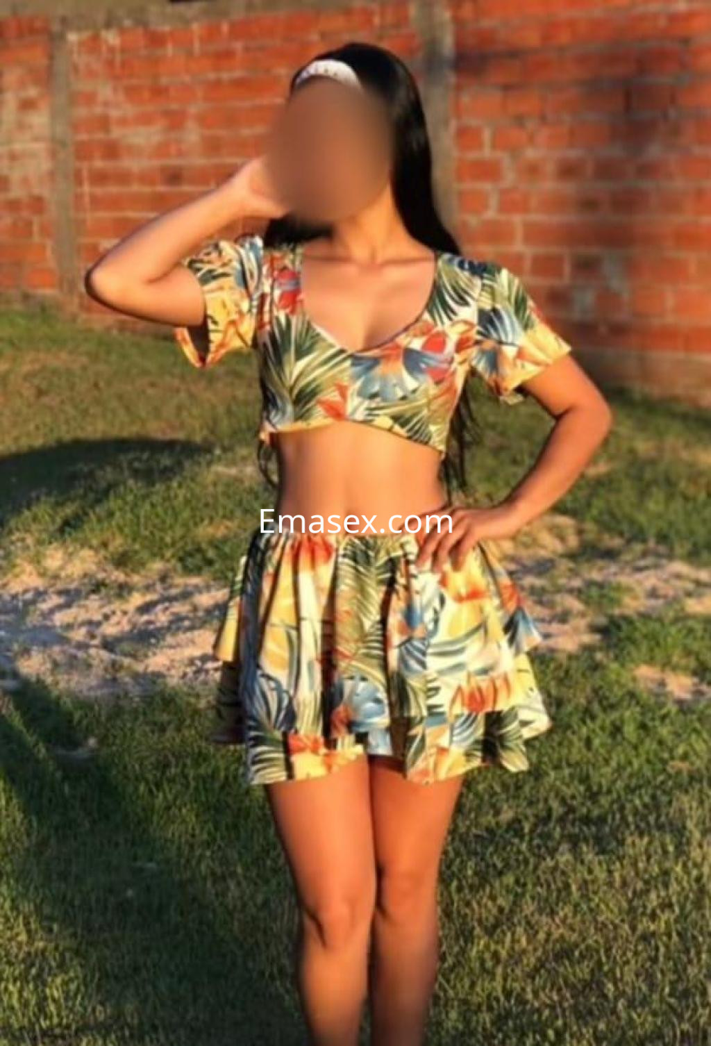 Escort en Cáceres con un vestido corto de estampado floral, posando en un entorno al aire libre.