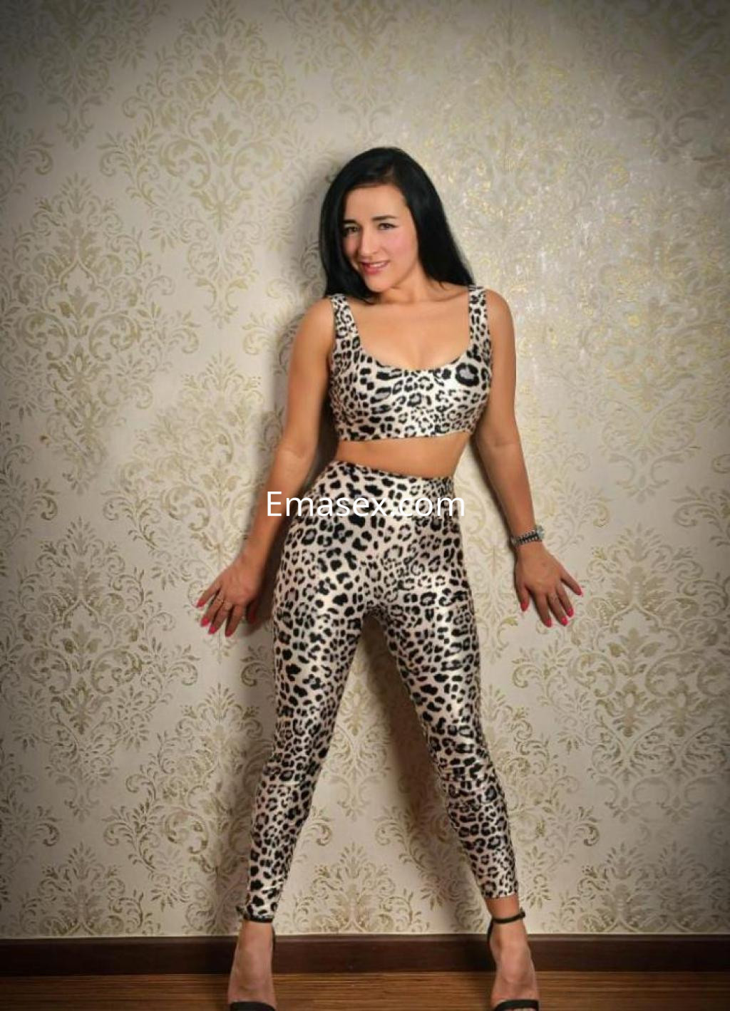 Puta posando con un conjunto de dos piezas de estampado de leopardo en un fondo decorativo en Girona.