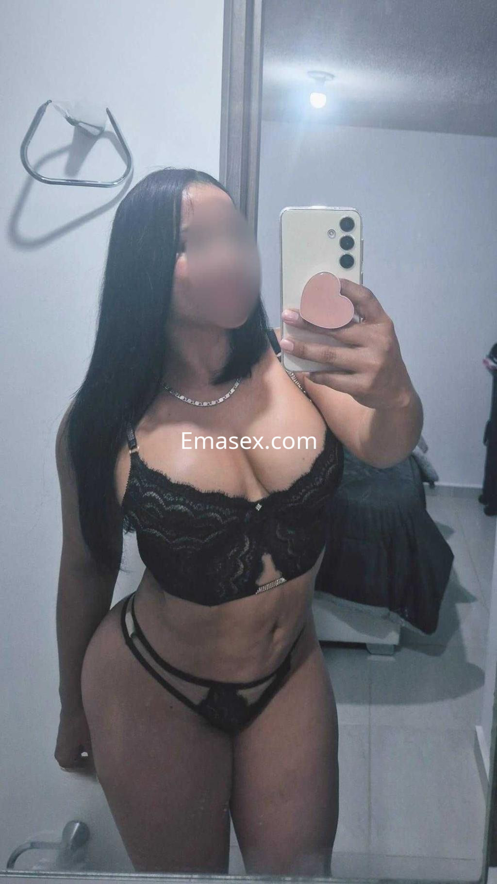 Escort en Granada posando frente al espejo con lencería negra, cabello largo y lacio, mostrando una figura curvilínea.