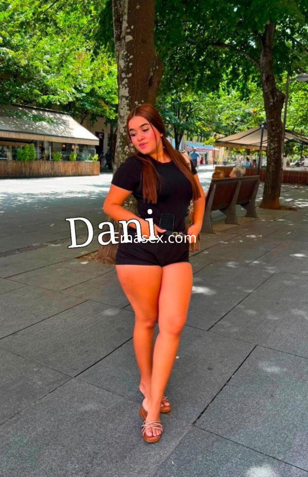 Puta posando en un parque de León, viste un conjunto negro ajustado que resalta su figura y tiene el cabello largo.