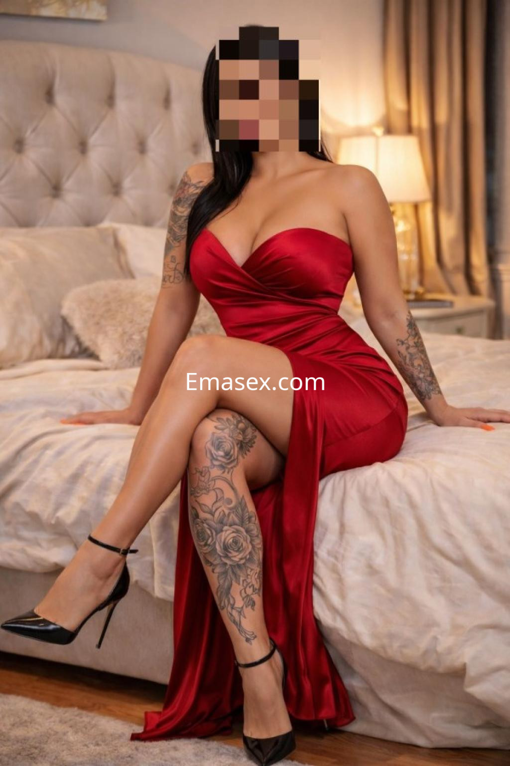 Puta sentada en una cama, luciendo un vestido rojo ajustado, con tatuajes visibles y tacones negros en Lleida.