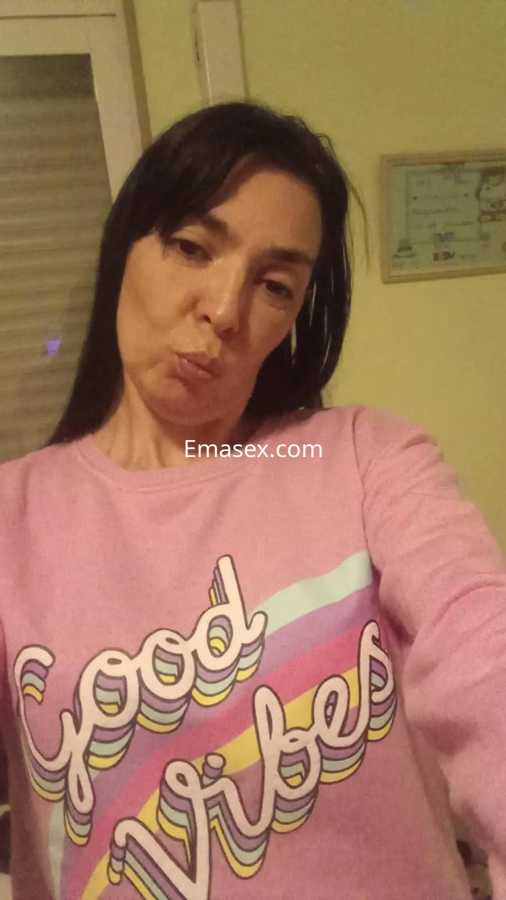 Puta en Málaga posando para una selfie con una sudadera rosa con el texto 