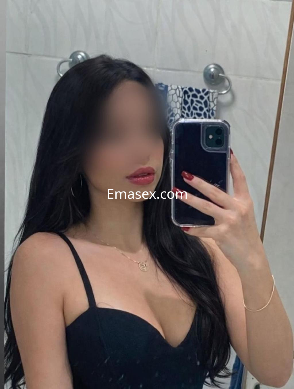 Puta de Pamplona posando en un espejo con un vestido negro, cabello largo y lacio, y labios pintados.