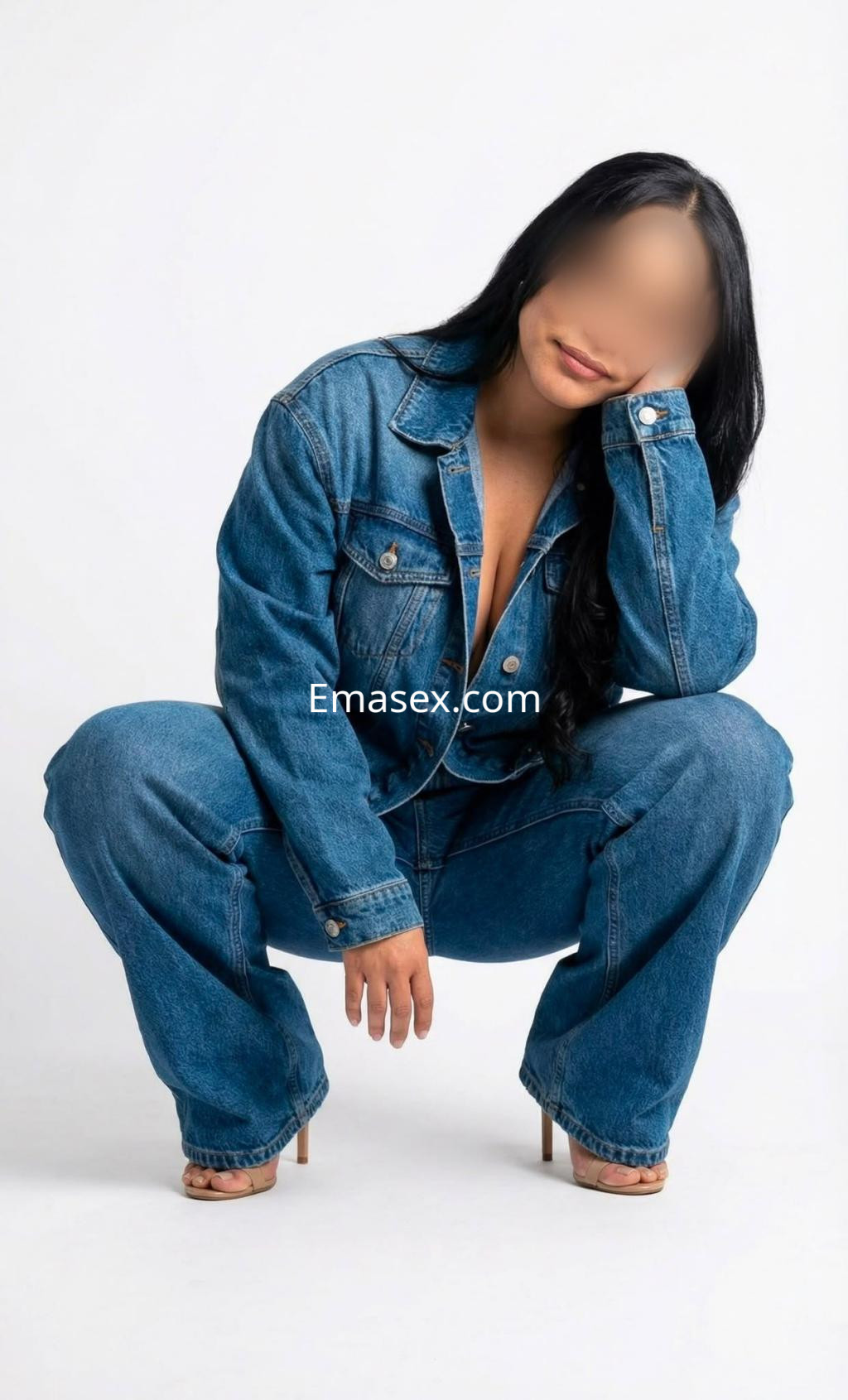 La puta viste un conjunto de denim y tacones, posando en cuclillas sobre un fondo claro en Pamplona.