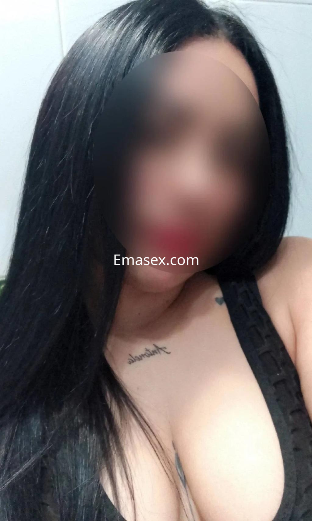 Escort con cabello largo y lacio, vistiendo un top negro de encaje, en un entorno interior de Málaga.