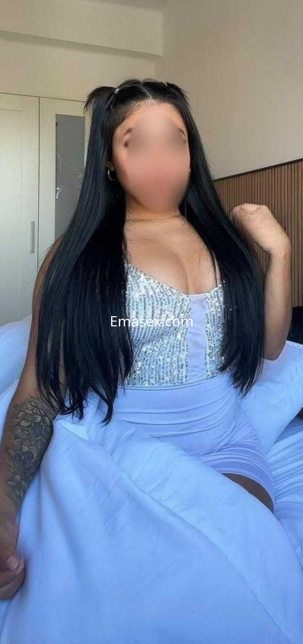 Escort en Vigo con cabello largo y lacio, luciendo un vestido ajustado de color claro y posando en una cama.
