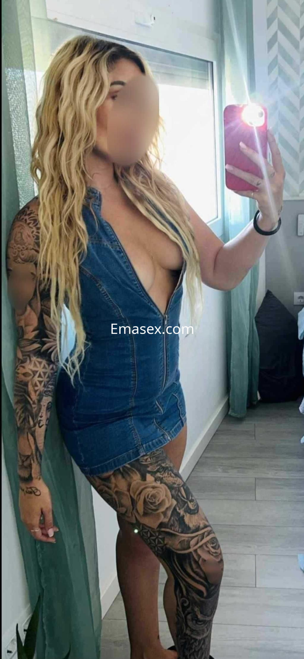 Puta en Madrid, con cabello rubio y largo, luciendo un vestido de mezclilla ajustado y tatuajes en su pierna.