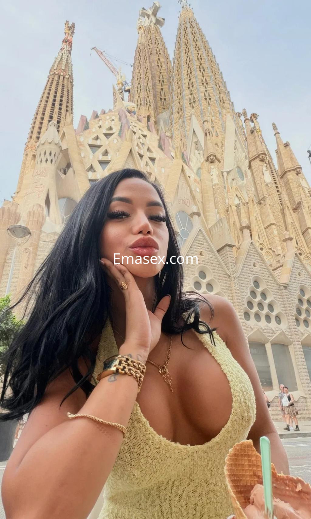 Escort en Zaragoza posa frente a la Sagrada Familia, luciendo un vestido amarillo y disfrutando de un helado.