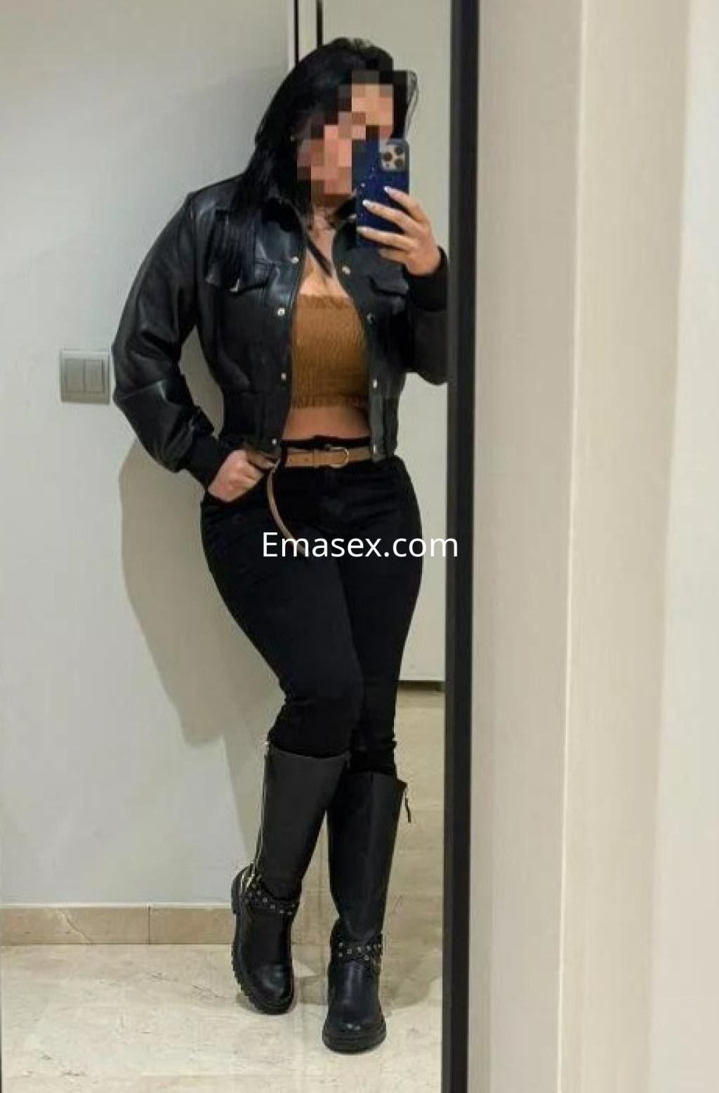 La puta se muestra en un espejo con chaqueta de cuero negra, top marrón y pantalones ajustados en Castellón.
