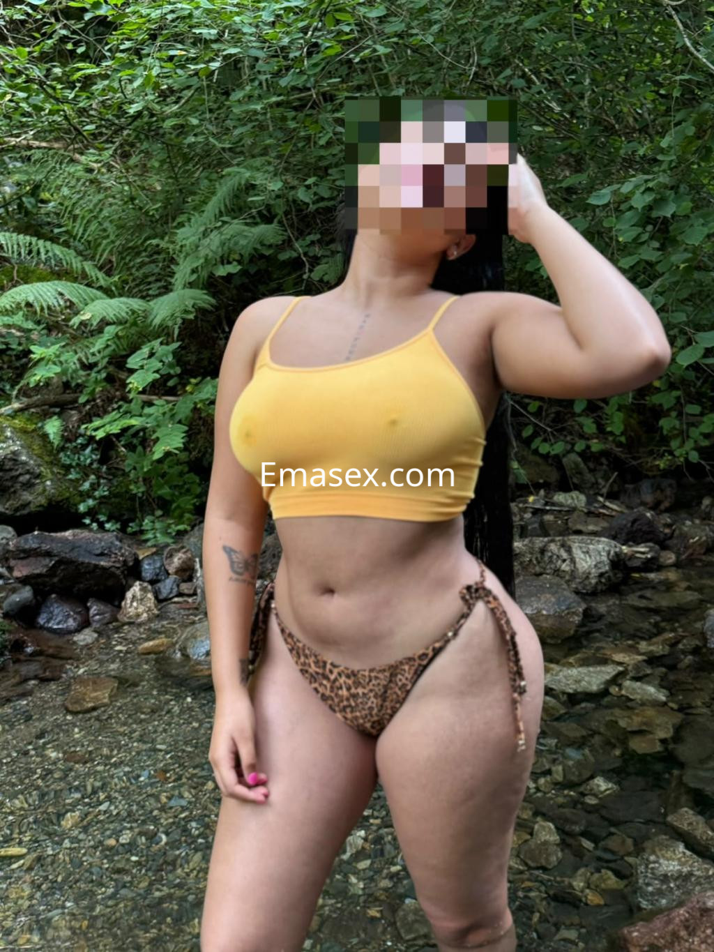 Puta de pie junto a un arroyo en Irún, vistiendo un top amarillo y una lencería de leopardo, con cabello largo.