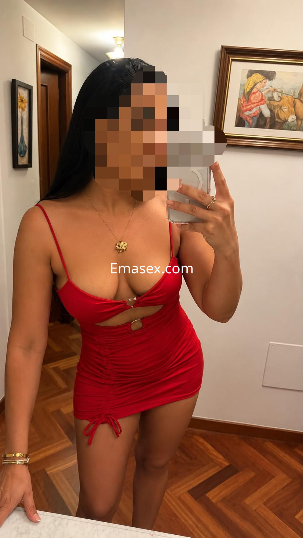 Puta en Santiago, posando frente a un espejo con un vestido rojo ajustado y tirantes delgados.