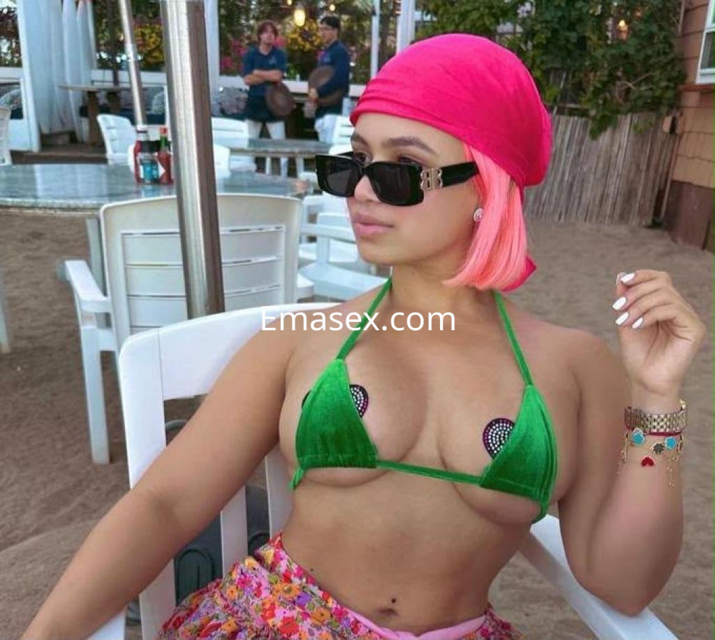 La puta luce un bikini verde con detalles brillantes, un pañuelo rosa y gafas de sol en Pamplona.