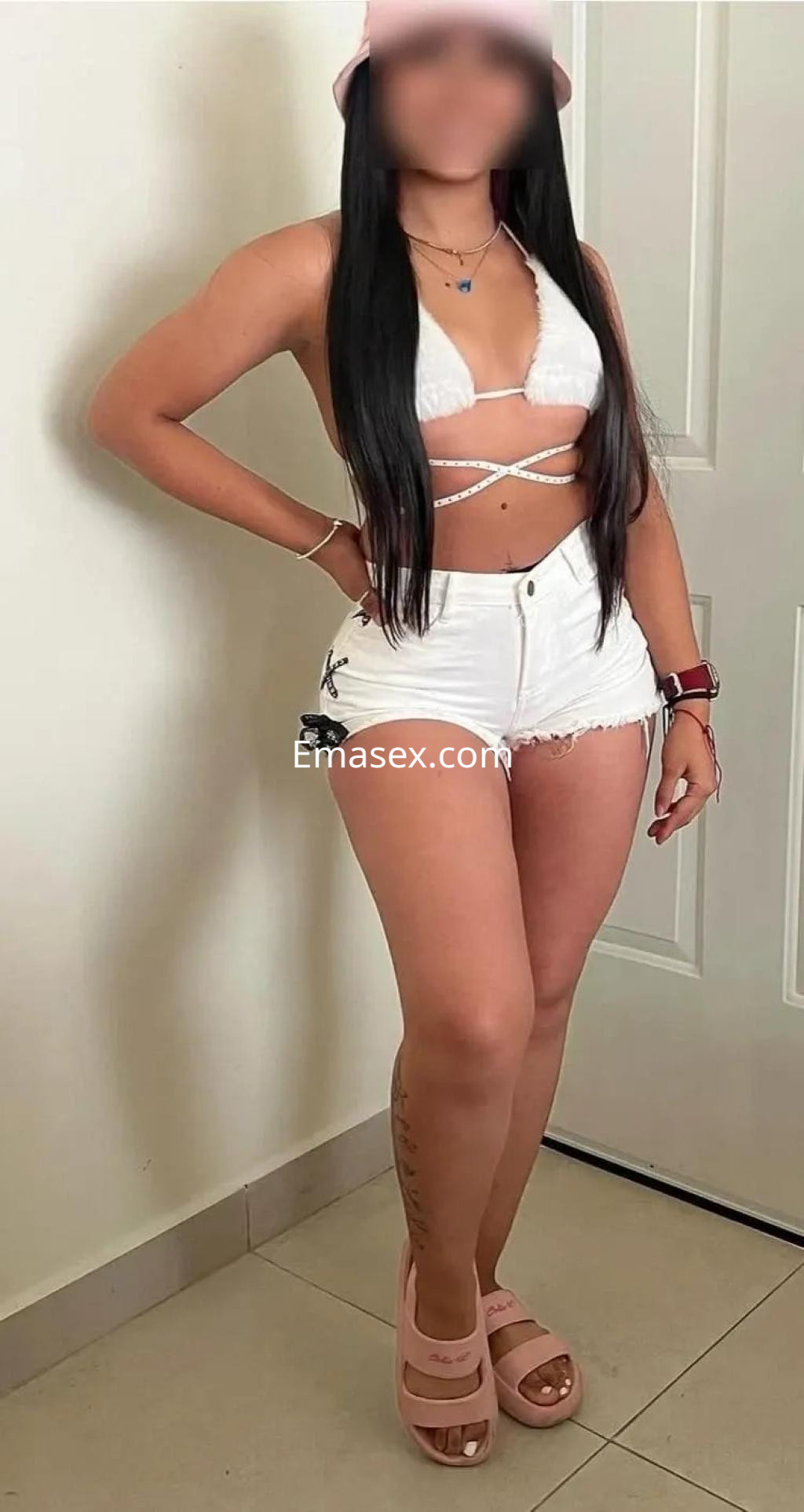 Escort en Coruña con top blanco y shorts cortos, posando con una actitud segura y sandalias rosadas.