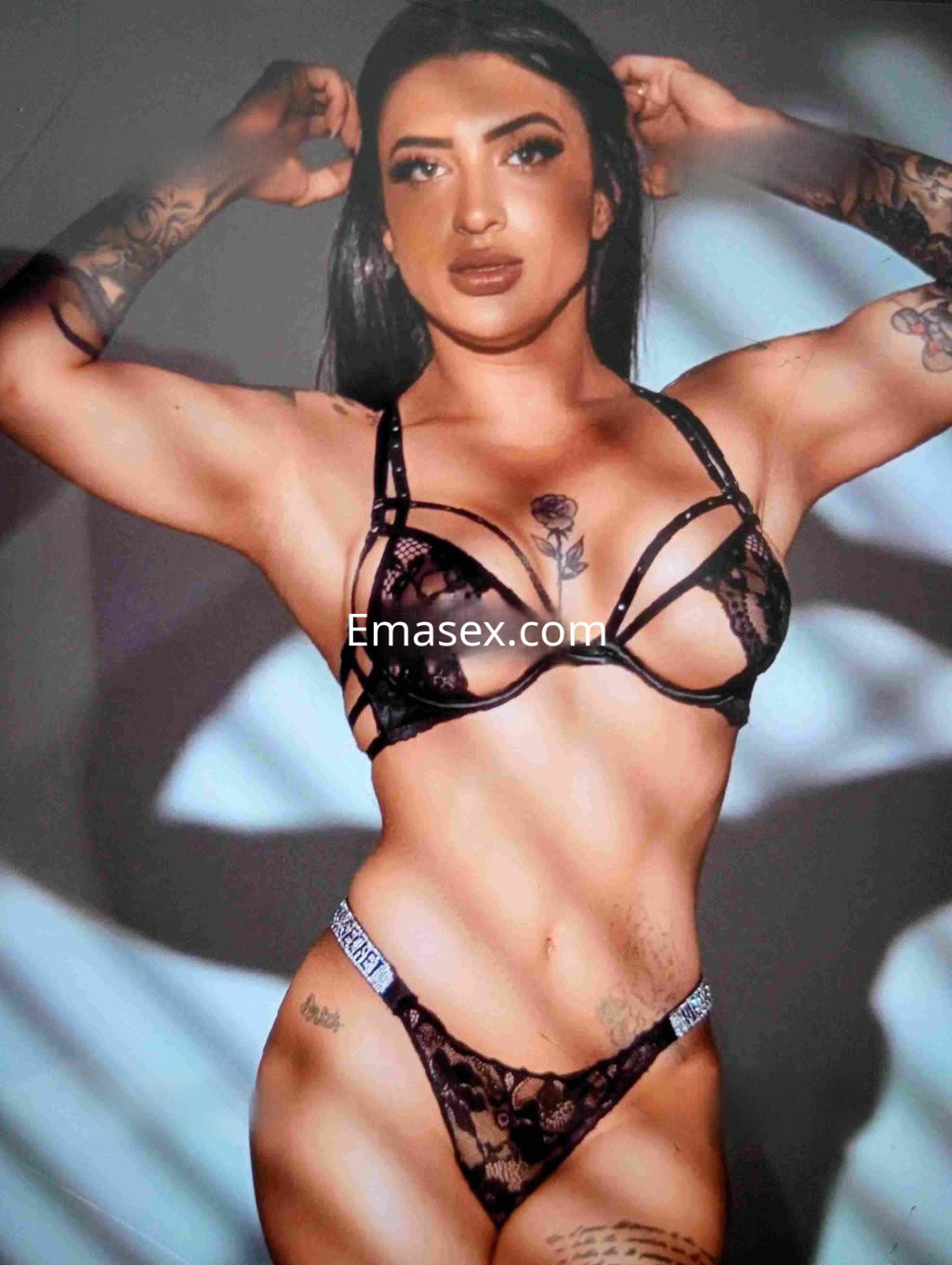Puta en Castellón posando con lencería negra, mostrando sus tatuajes y una actitud seductora.