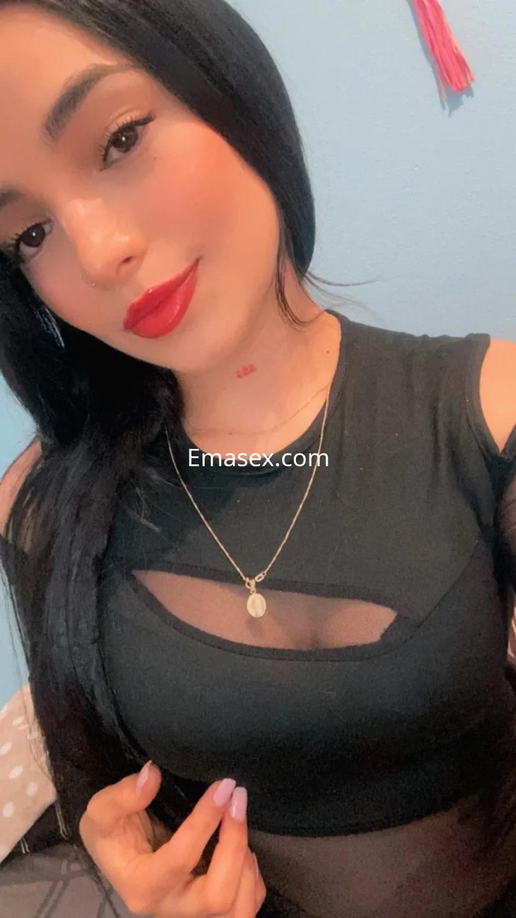 Escort en Córdoba con cabello largo y lacio, viste una blusa negra con detalles transparentes y labios rojos.