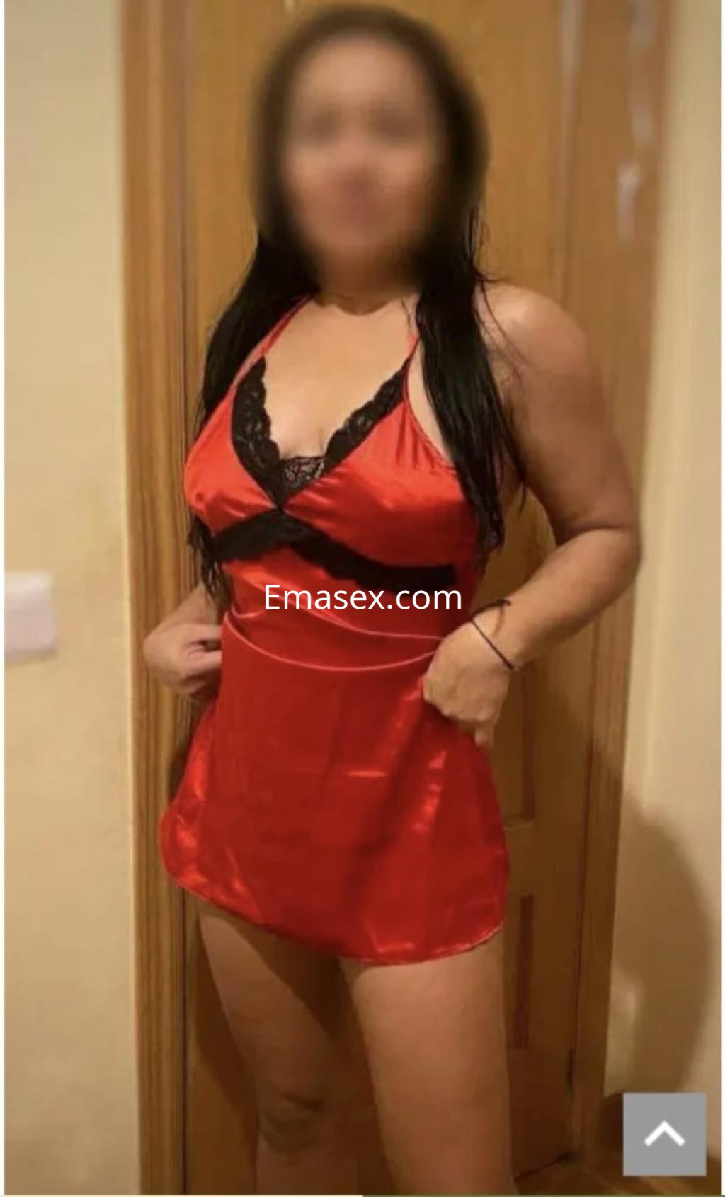 La puta viste un vestido rojo satinado con encaje negro, posando en un interior de Granada.