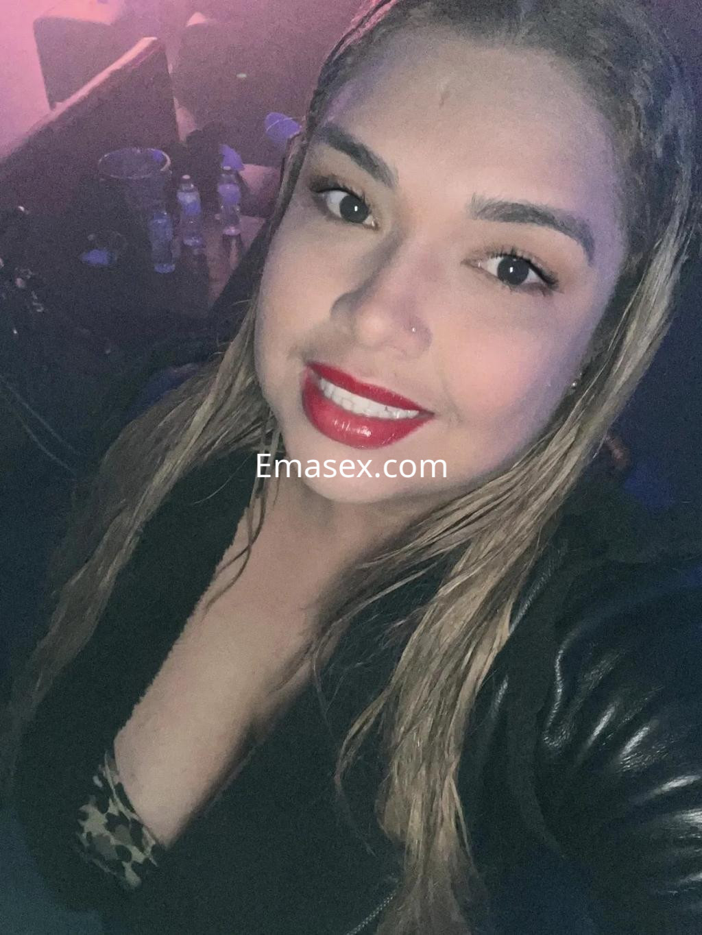 Escort en Granada posando con cabello largo y lacio, maquillaje resaltando sus labios rojos y una blusa con estampado.