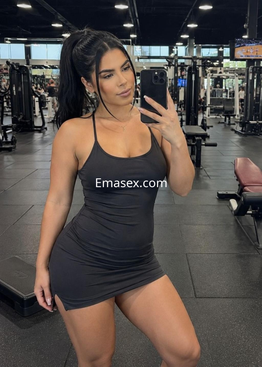 Puta en Granada luciendo un vestido negro ajustado mientras se toma una selfie en el gimnasio.