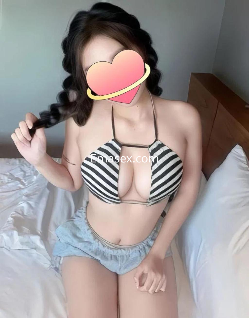 Puta con cabello trenzado, vistiendo un bikini de rayas y pantalones cortos, en una habitación en Logroño.