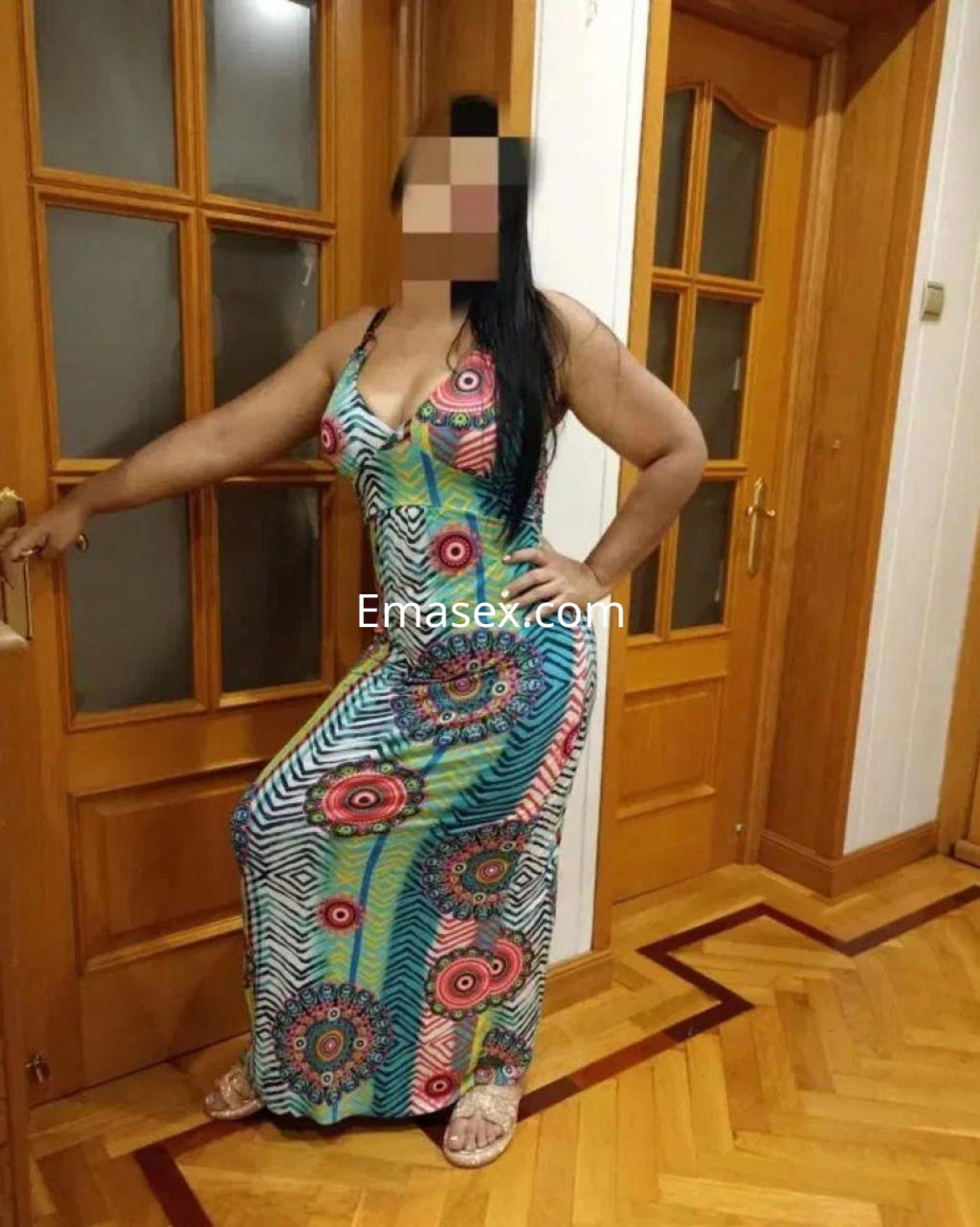 Puta posando de pie en una habitación con una vestido largo y colorido, mostrando un look elegante en Zamora.