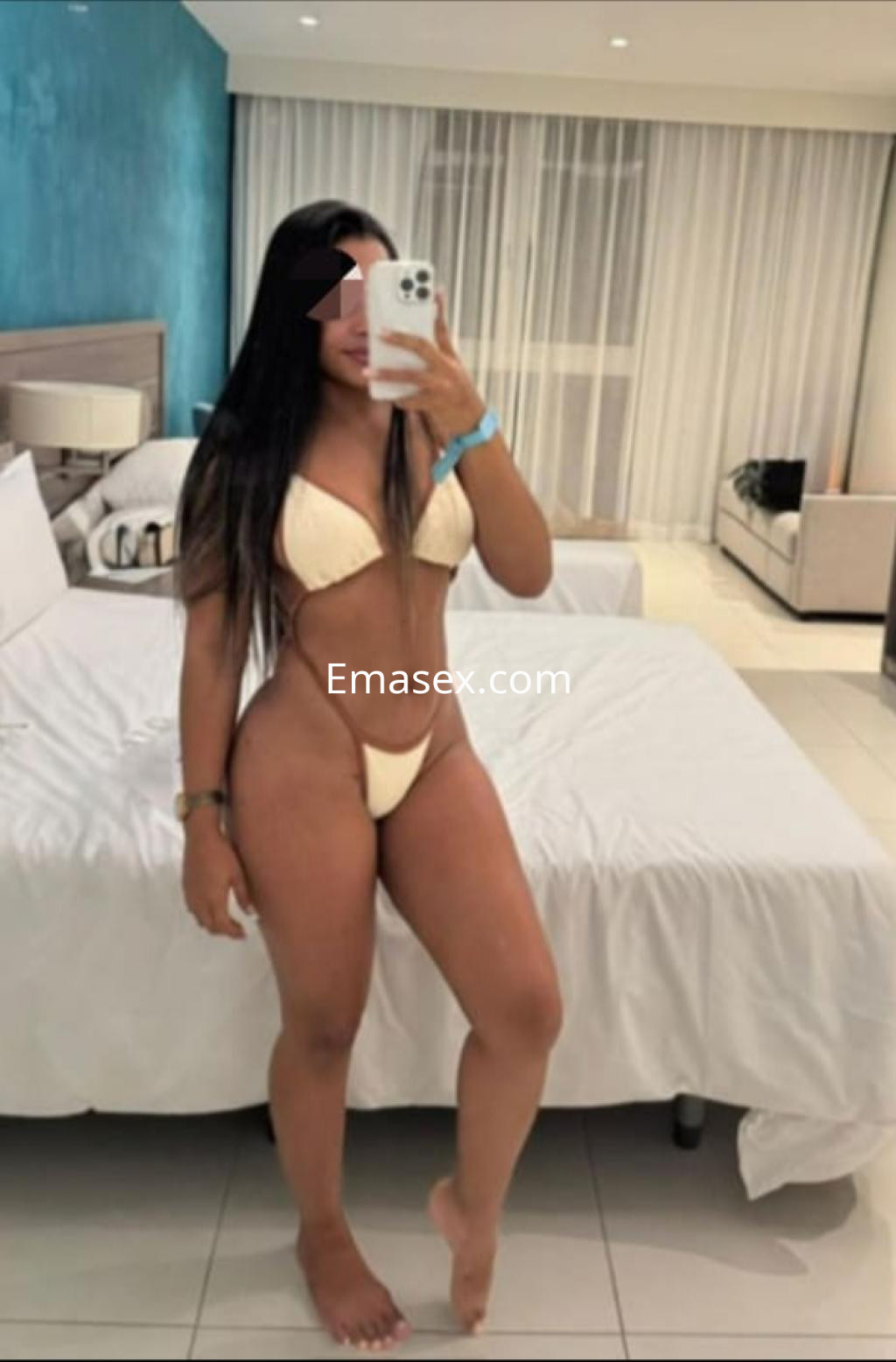 Escort en Santiago posando en una habitación con paredes azules, vistiendo un bikini claro y mostrando su figura.