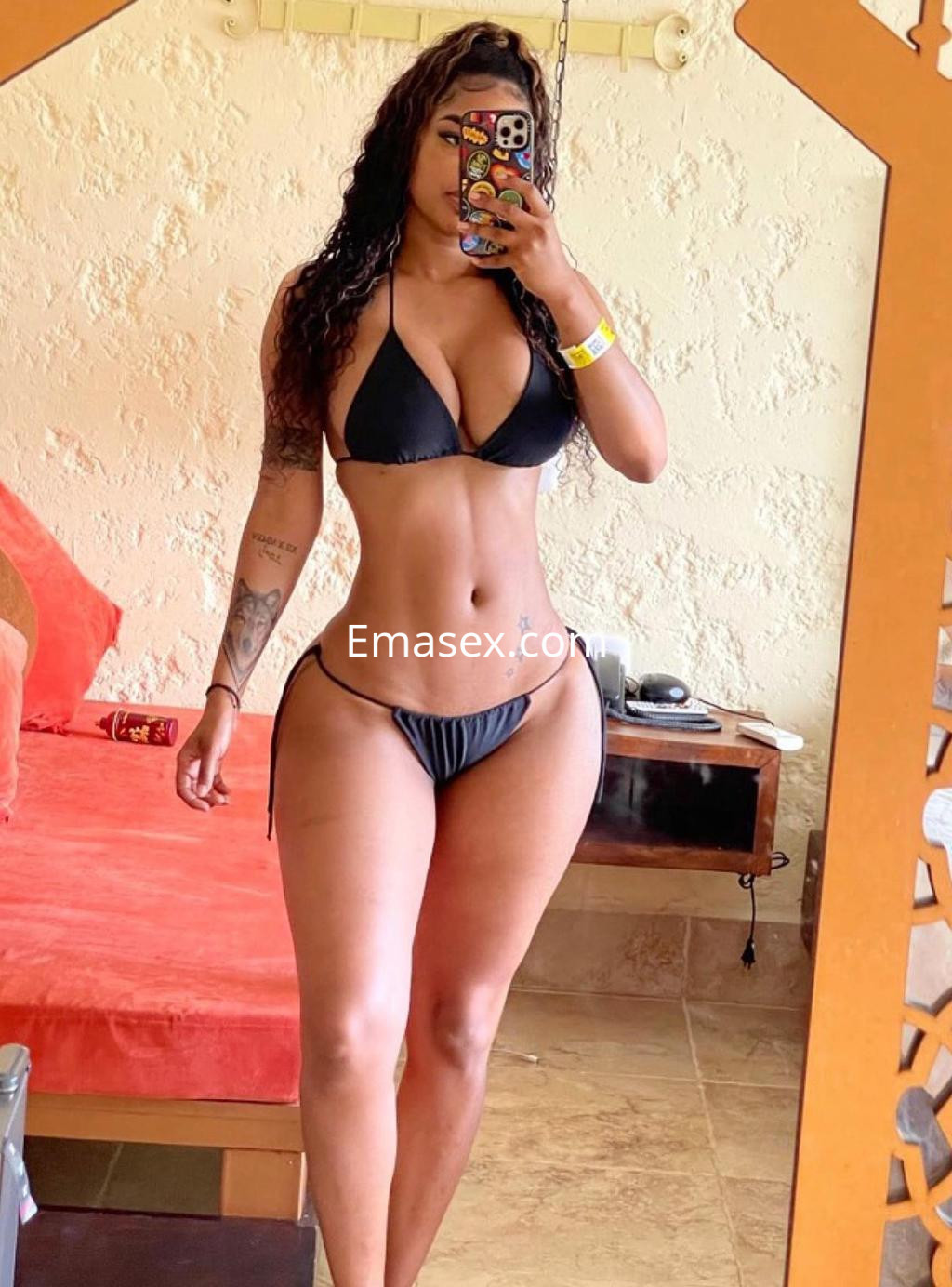 La puta posa frente al espejo con un bikini negro, mostrando su figura tonificada en un ambiente acogedor de Málaga.