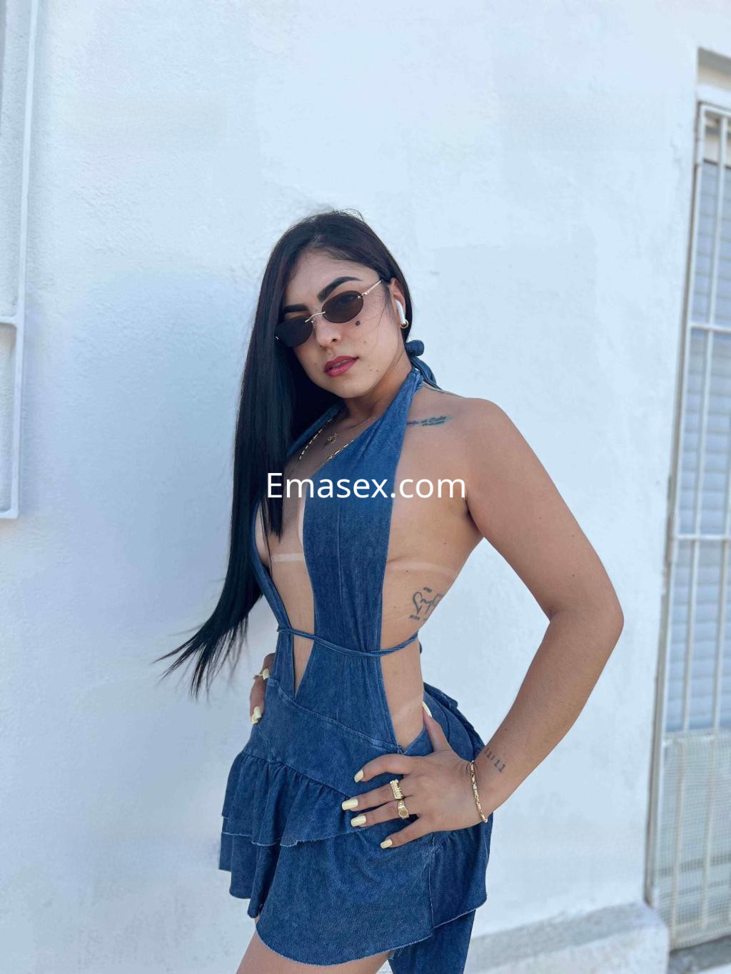 Puta en Alicante viste un vestido de mezclilla con escote pronunciado y gafas de sol, mostrando una pose segura.