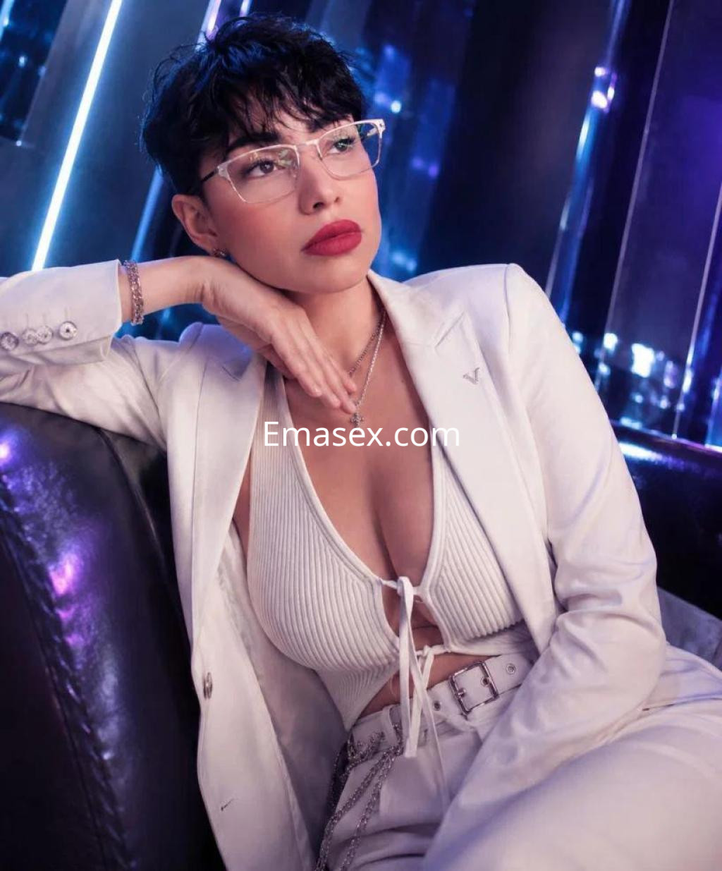 Escort en Barcelona con traje blanco y top ajustado, posando de manera elegante en un ambiente moderno.