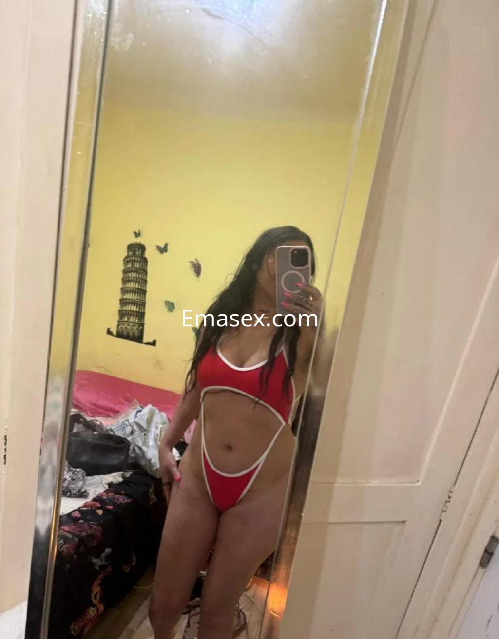 Puta en Ourense muestra su figura en un traje de baño rojo con detalles blancos frente a un espejo.
