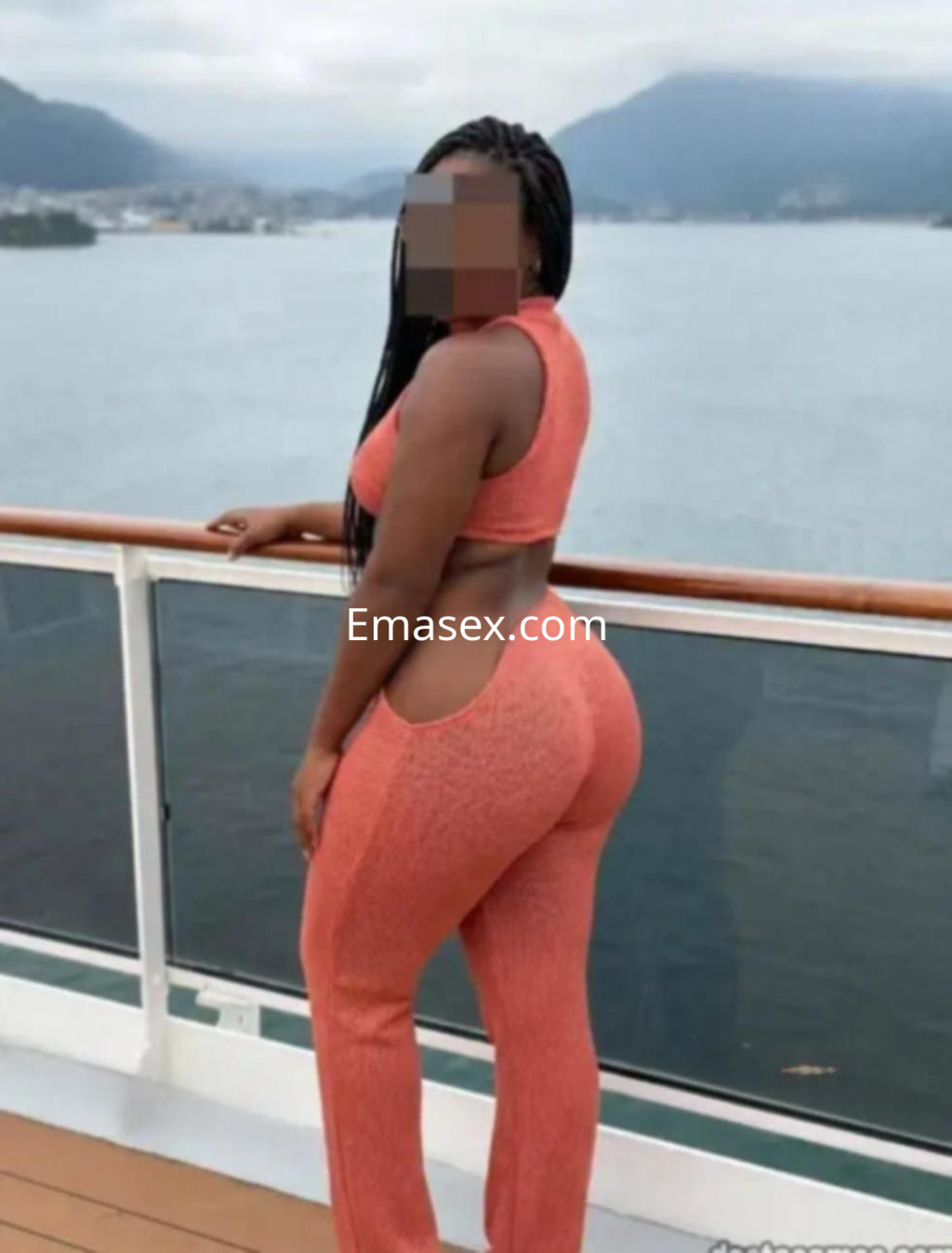 La puta viste un conjunto de dos piezas naranja mientras posa de espaldas con vista al mar en Vigo.