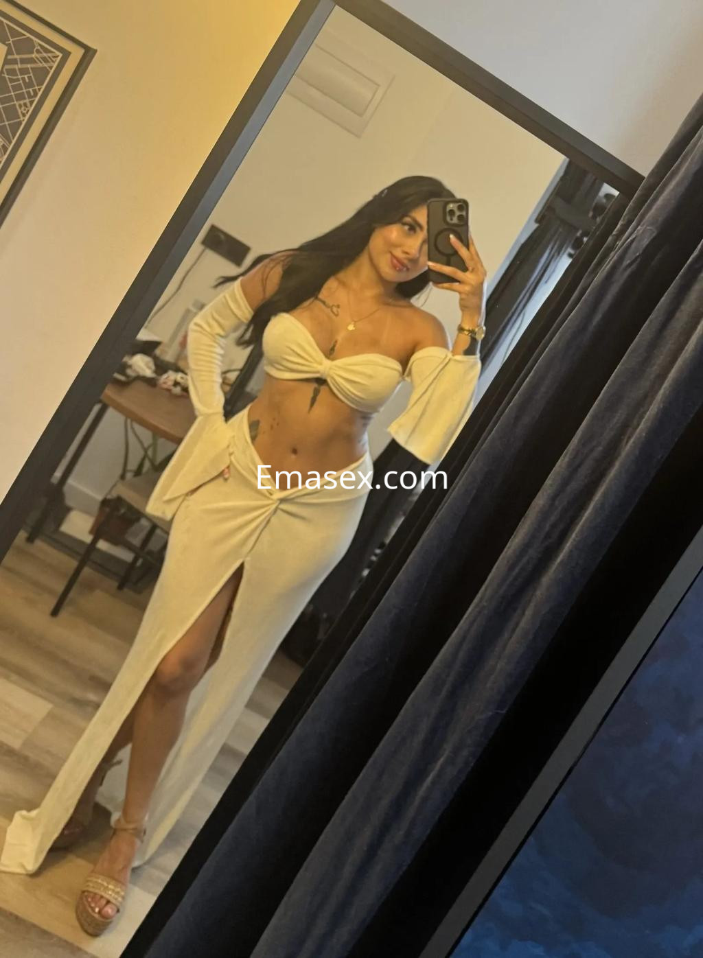 Escort en Valencia, posando en un espejo con un conjunto blanco de dos piezas que resalta su figura.
