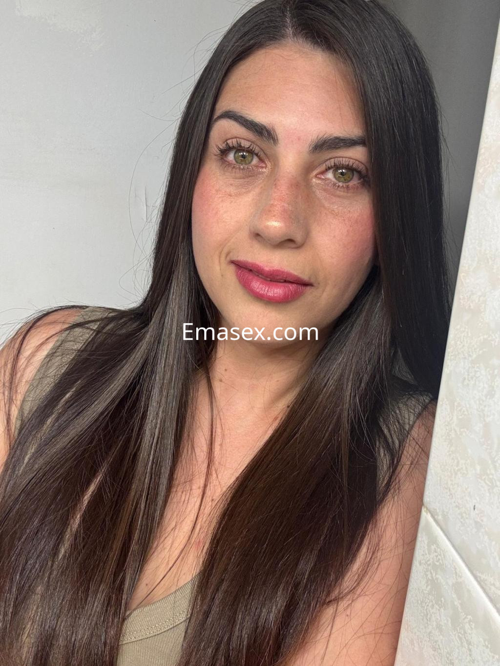 Puta con cabello largo y lacio, luciendo un maquillaje sutil y un top claro, en un entorno luminoso en Vitoria.