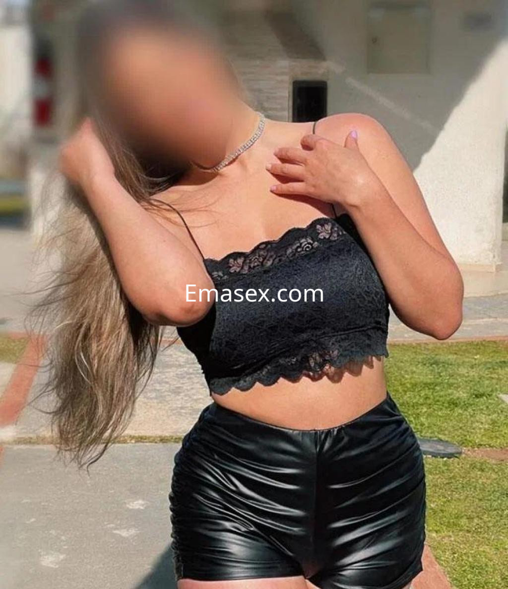 Puta en Vitoria, luciendo un top negro de encaje y pantalones cortos de cuero, con cabello largo y lacio.