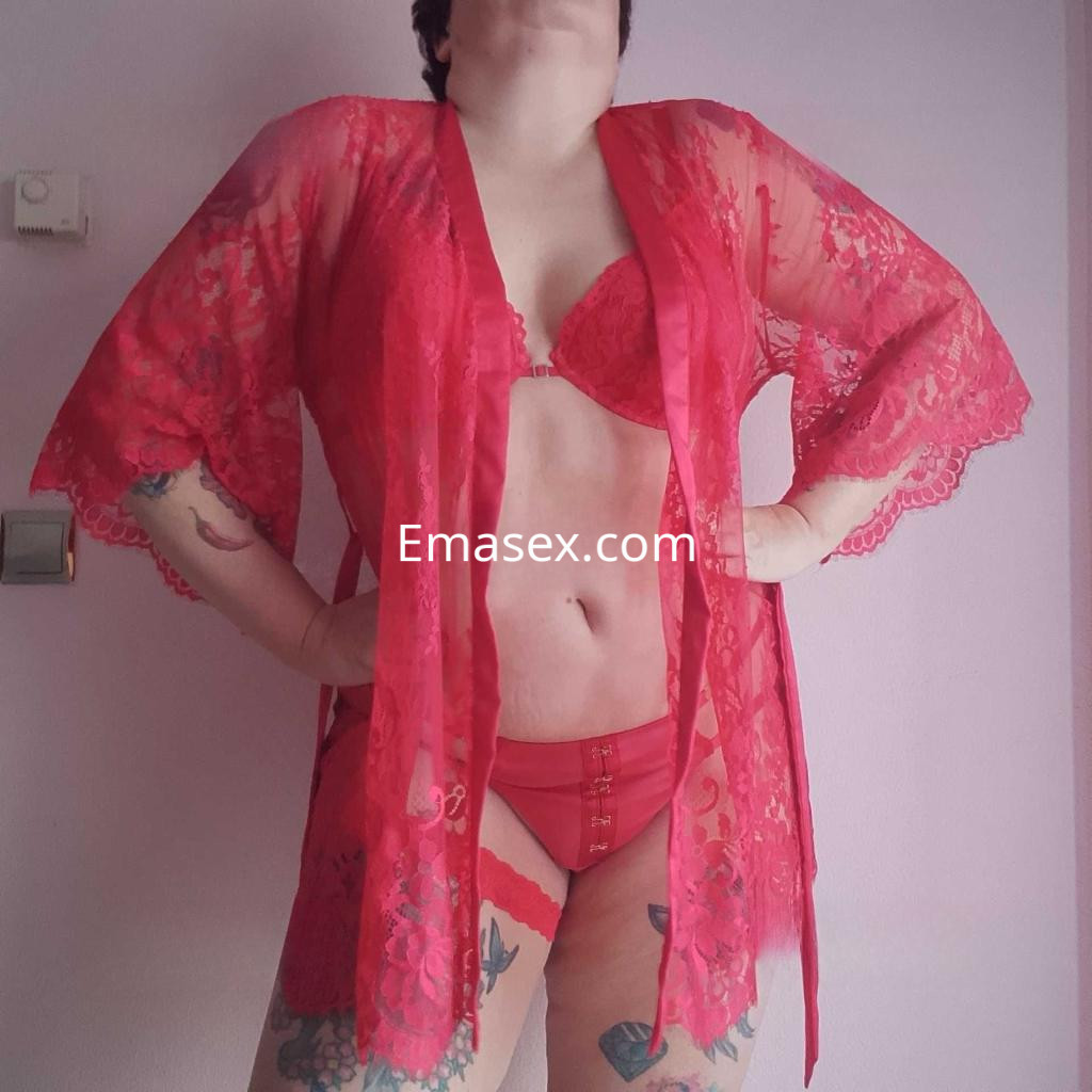Escort en Alicante luciendo un conjunto de lencería roja con encaje y un kimono transparente, posando con confianza.