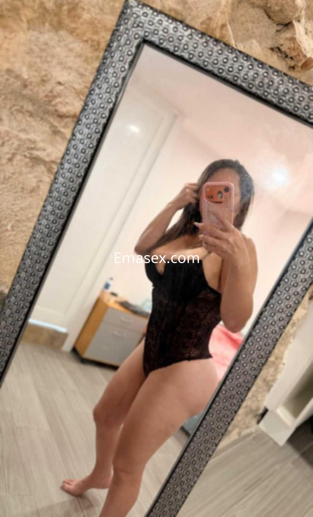 Escort en Barcelona posando en un espejo, luciendo un body negro y mostrando su figura con confianza.