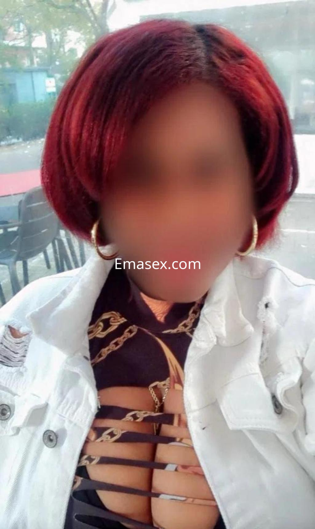 Escort en Barcelona con cabello corto y rojizo, vistiendo una camiseta de diseño atrevido y chaqueta blanca.