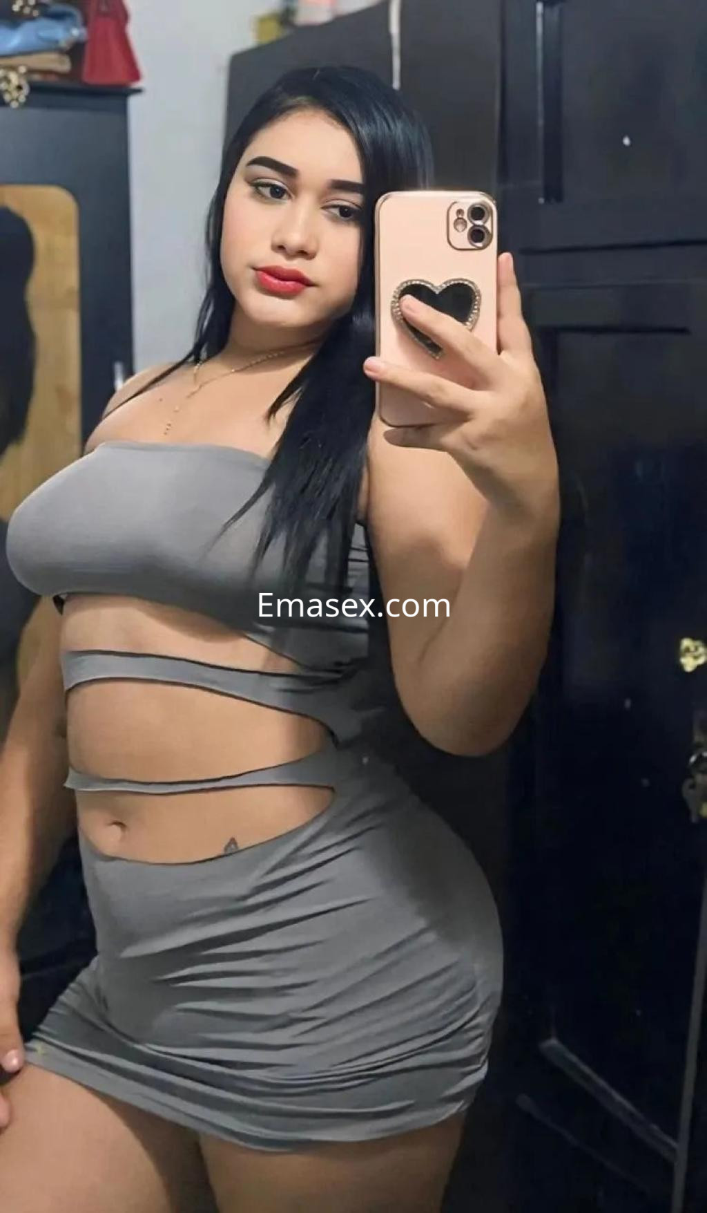 La puta en Córdoba se muestra en un vestido gris ajustado que resalta su figura, con cabello largo y lacio.