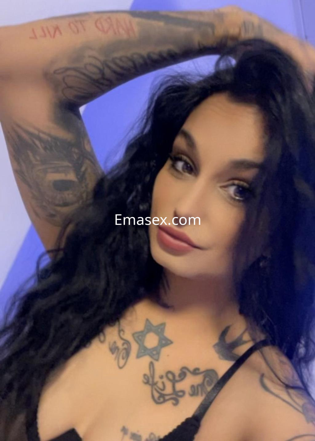 Puta con cabello largo y negro, luciendo un top negro y exhibiendo varios tatuajes en su brazo y pecho en Córdoba.
