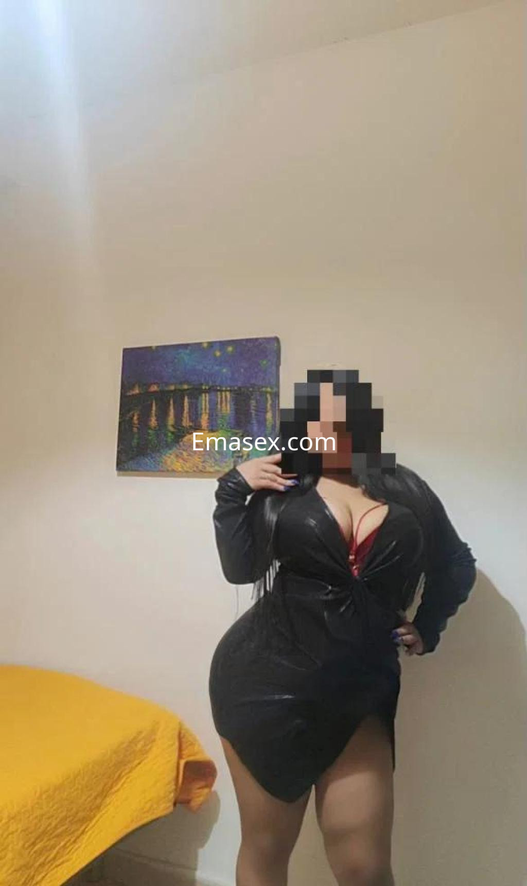 Puta en Granada, con un vestido de cuero negro que resalta su figura, posando en un entorno interior.