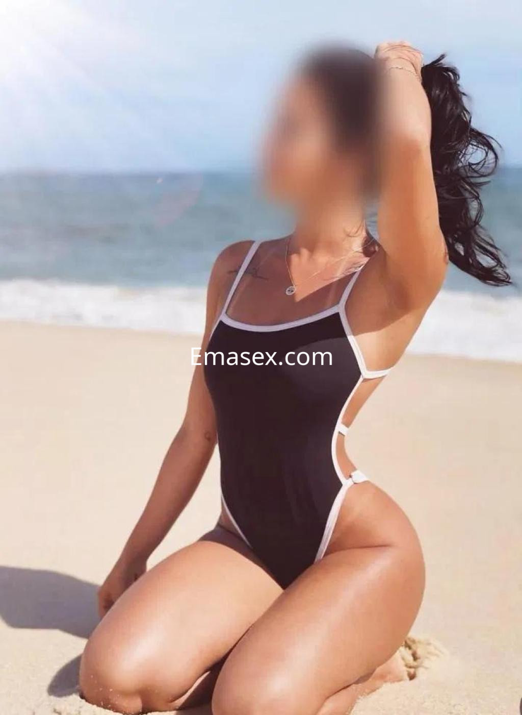 Puta en Lugo posando en la playa con un bañador negro, resaltando su figura y peinada con coleta.