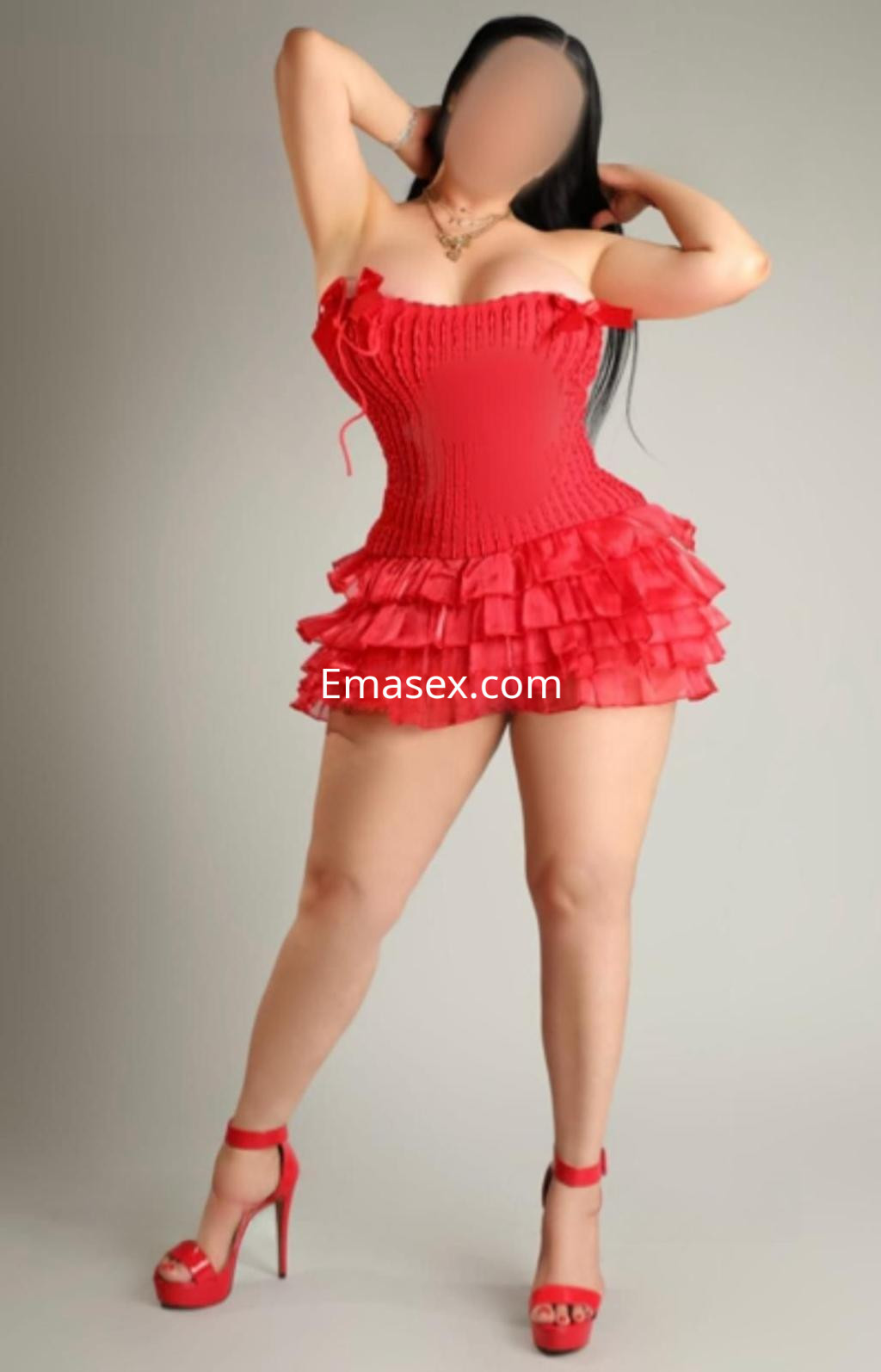 Puta de piel clara en Madrid, luciendo un vestido rojo ajustado con volantes y tacones altos.