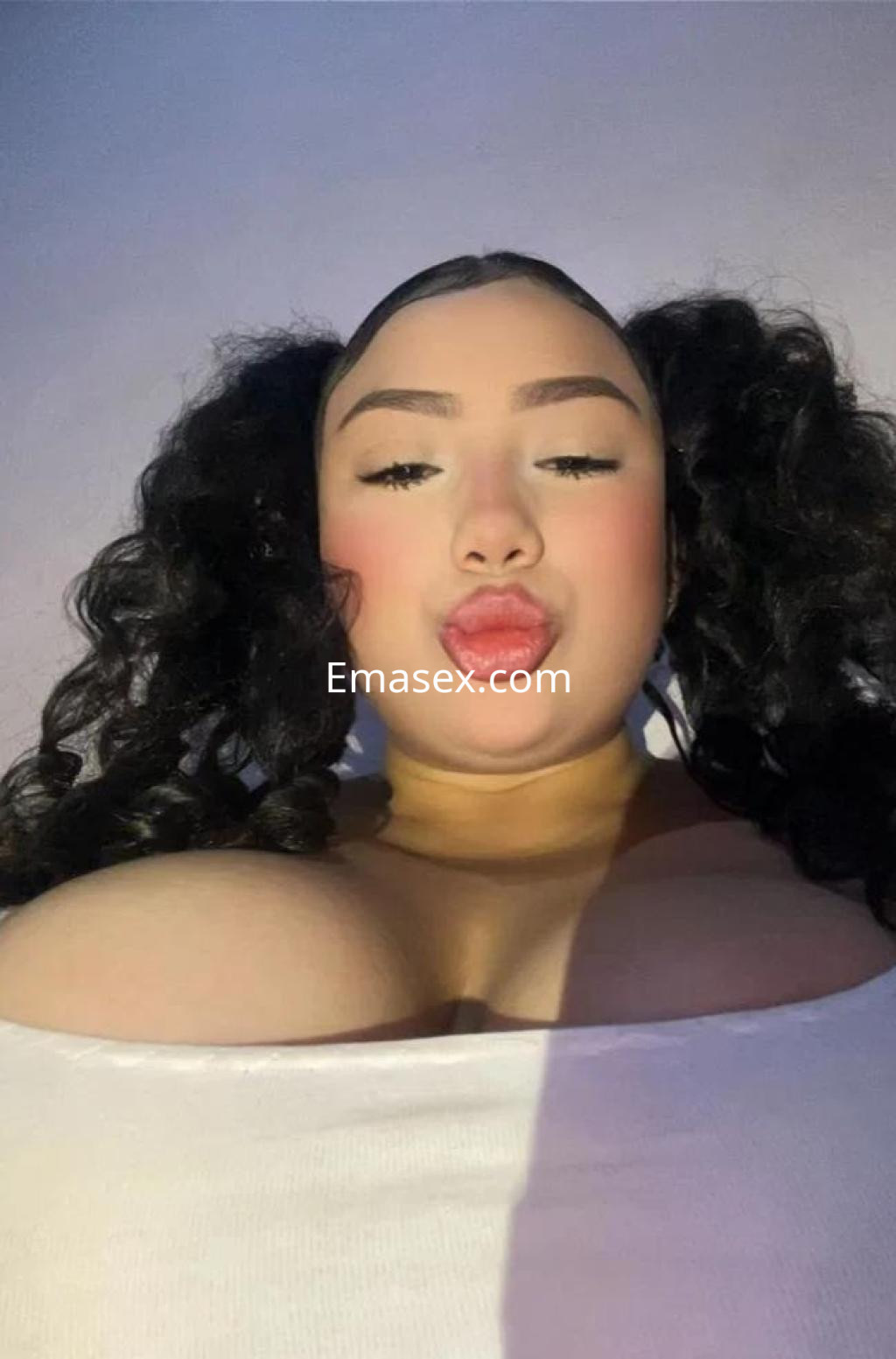 Puta con cabello rizado y dos coletas, viste una blusa blanca que resalta su figura en Tarragona.