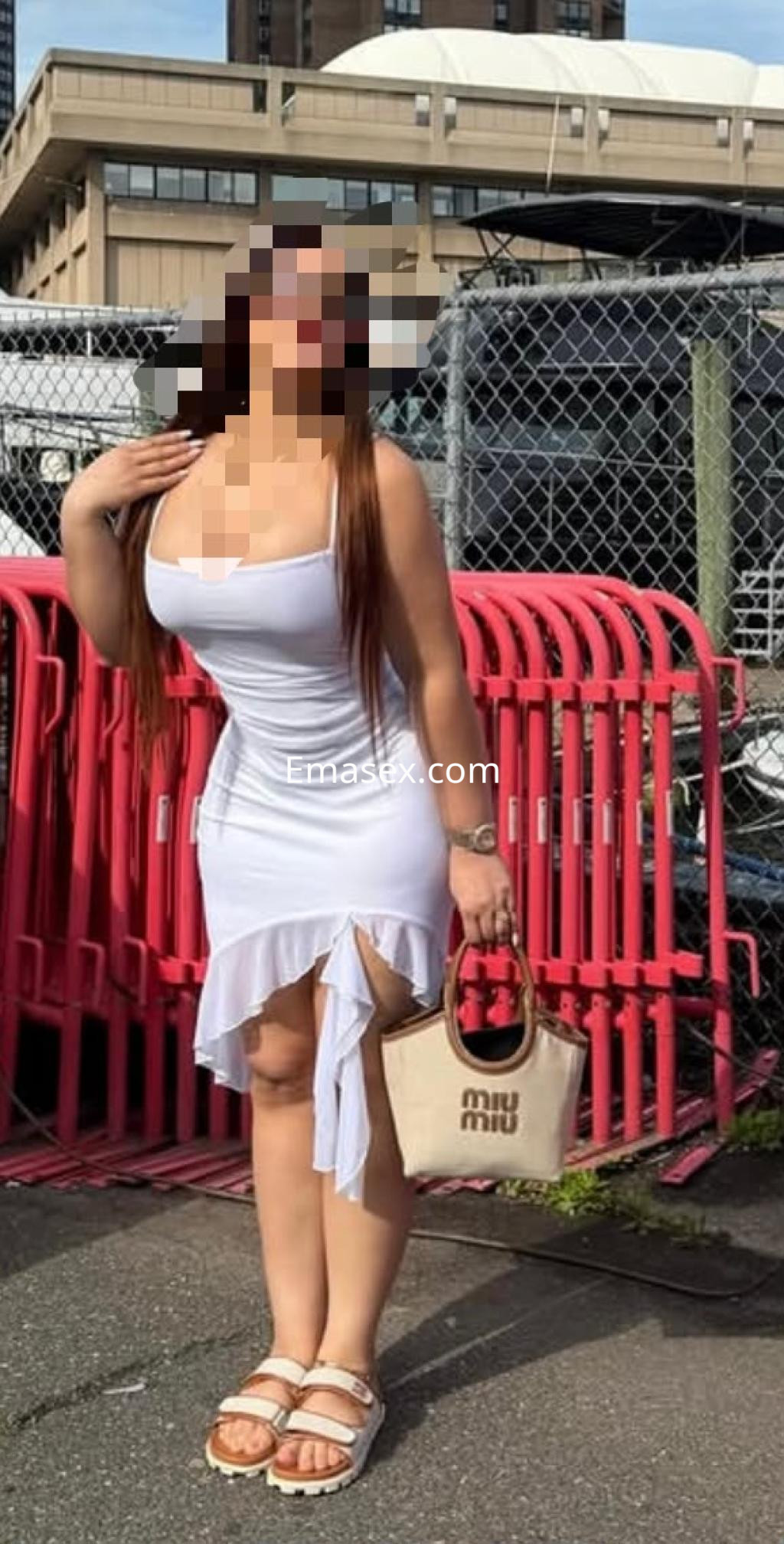 Puta de Vitoria luciendo un vestido blanco ceñido con detalles en la falda y sandalias, posando en un entorno urbano.