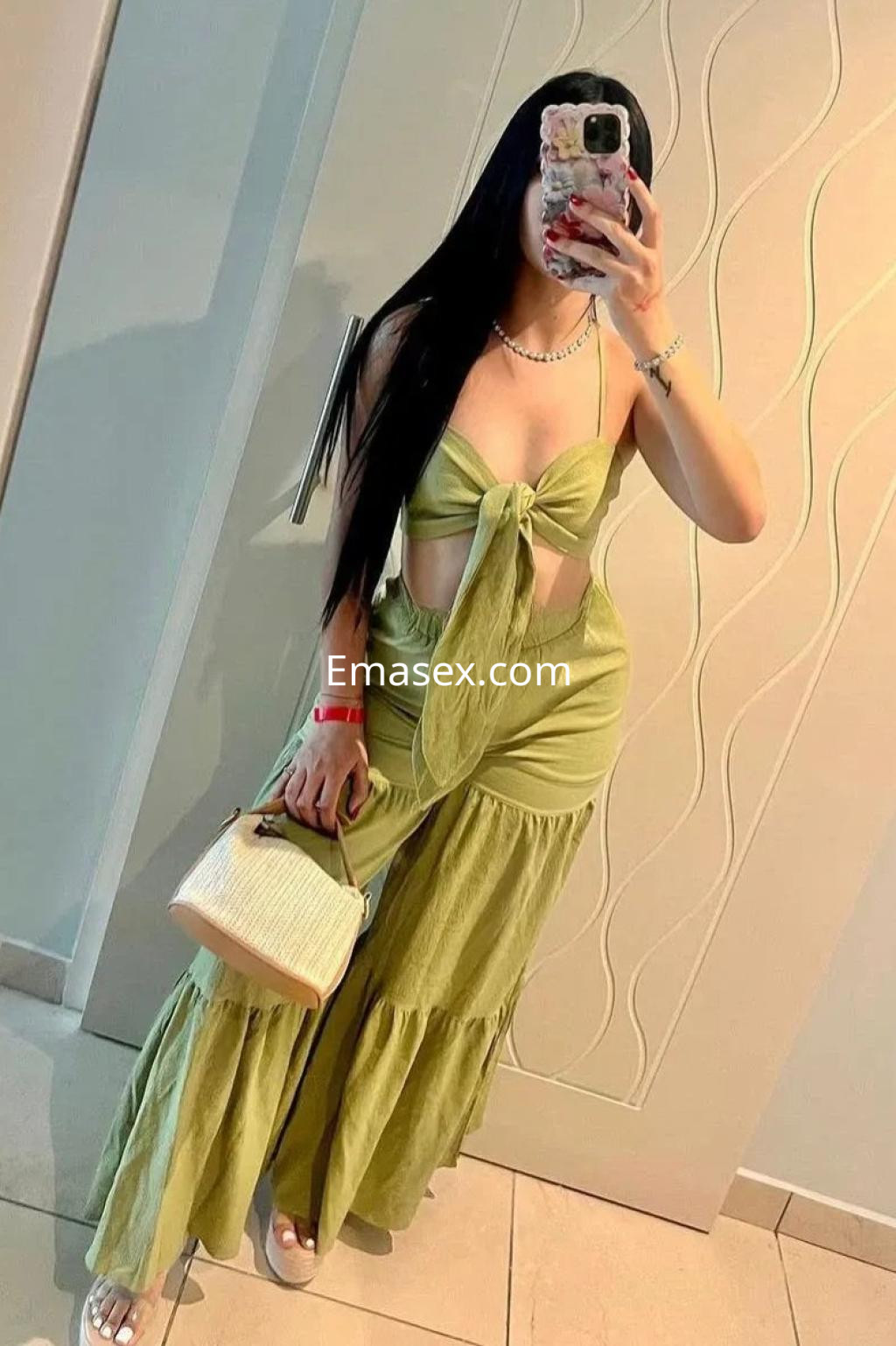 Escort en Cádiz con cabello largo y negro, luciendo un conjunto verde claro de dos piezas y sandalias blancas.